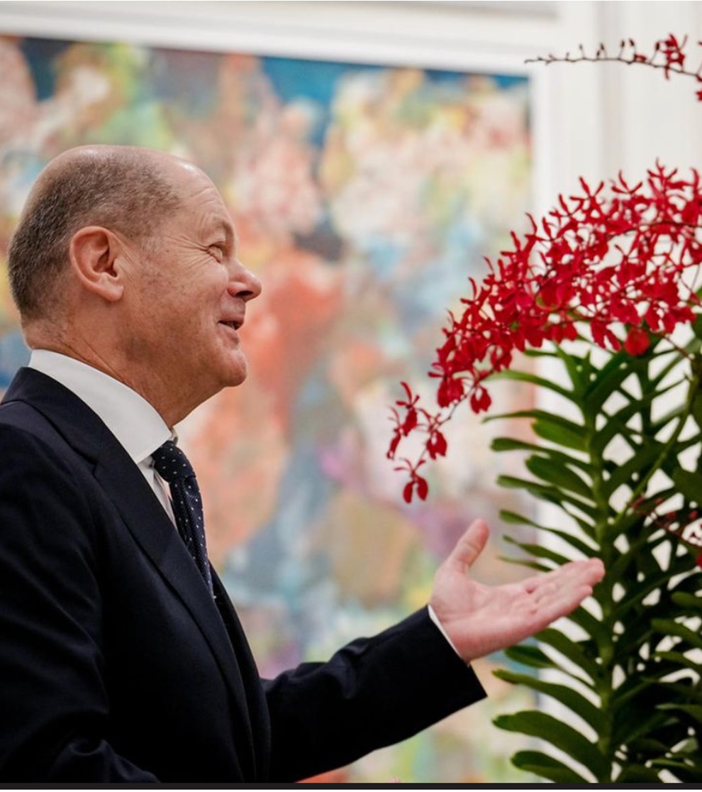 Bundeskanzler Scholz bei der Rede zum Thema Barrierefreiheit bei der dc:connect mit Blumen geschmückten Rednerpult der dc AG